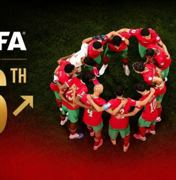 Morocco climb to sixth in latest FIFA rankings **Edited prompt (adapted to the FIFA rankings news angle):** Create a high-quality editorial sports news cover image with a premium international magazine aesthetic. Use **only the attached Morocco national team image**. Do not introduce any AI-generated players, backgrounds, or additional imagery. **Critical preservation instructions:** * Do **not** regenerate, modify, retouch, or alter any player, coach, or person in the image. * Do **not** change facial features, expressions, skin tones, hair, uniforms, or body proportions. * Do **not** enhance, recolour, or correct the original image colours. * Use the attached image exactly as provided while preserving every authentic detail. Present the Morocco national team in a powerful, clean editorial composition that conveys prestige, achievement, and international recognition after reaching the **2026 FIFA World Cup quarter-finals** and climbing to **6th in the FIFA Men's World Rankings**. Integrate a **large, elegant "6th"** into the composition using premium editorial typography. Position it naturally so it complements the image without covering key faces or important details. Place the **official FIFA logo** beside or above the ranking in a refined, professional manner. Add a subtle **upward movement icon (↗ or upward arrow)** next to the ranking to visually communicate Morocco's rise in the standings. The icon should feel sophisticated and understated rather than flashy. Apply a **soft red gradient overlay** across the bottom of the image, fading upward gently without obscuring the players. The gradient should add depth and create space for headlines while reinforcing Morocco's national colours. Style: premium editorial sports cover similar to a world-class publication such as *The Athletic*, *L'Équipe*, *BBC Sport*, or *The New York Times Sports*. Clean composition, subtle cinematic lighting, high contrast, realistic textures, slight dark vignette around the edges, and a polished, award-winning graphic design aesthetic. Morocco climb to sixth in latest FIFA rankings